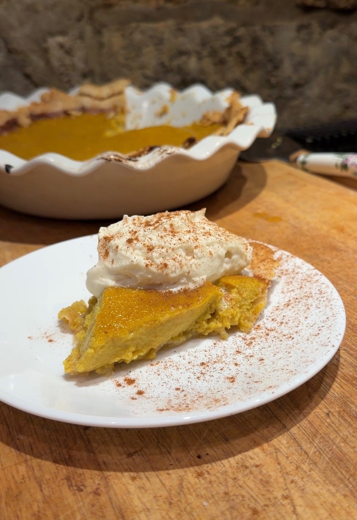 Slice of homemade pumpkin pie with a tallow crust and whipped cream