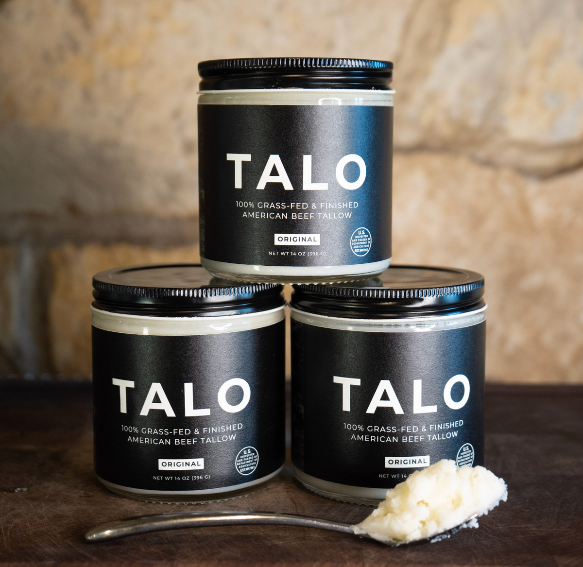 Three jars of TALO 100% grass-fed and finished American beef tallow stacked with a spoonful of tallow