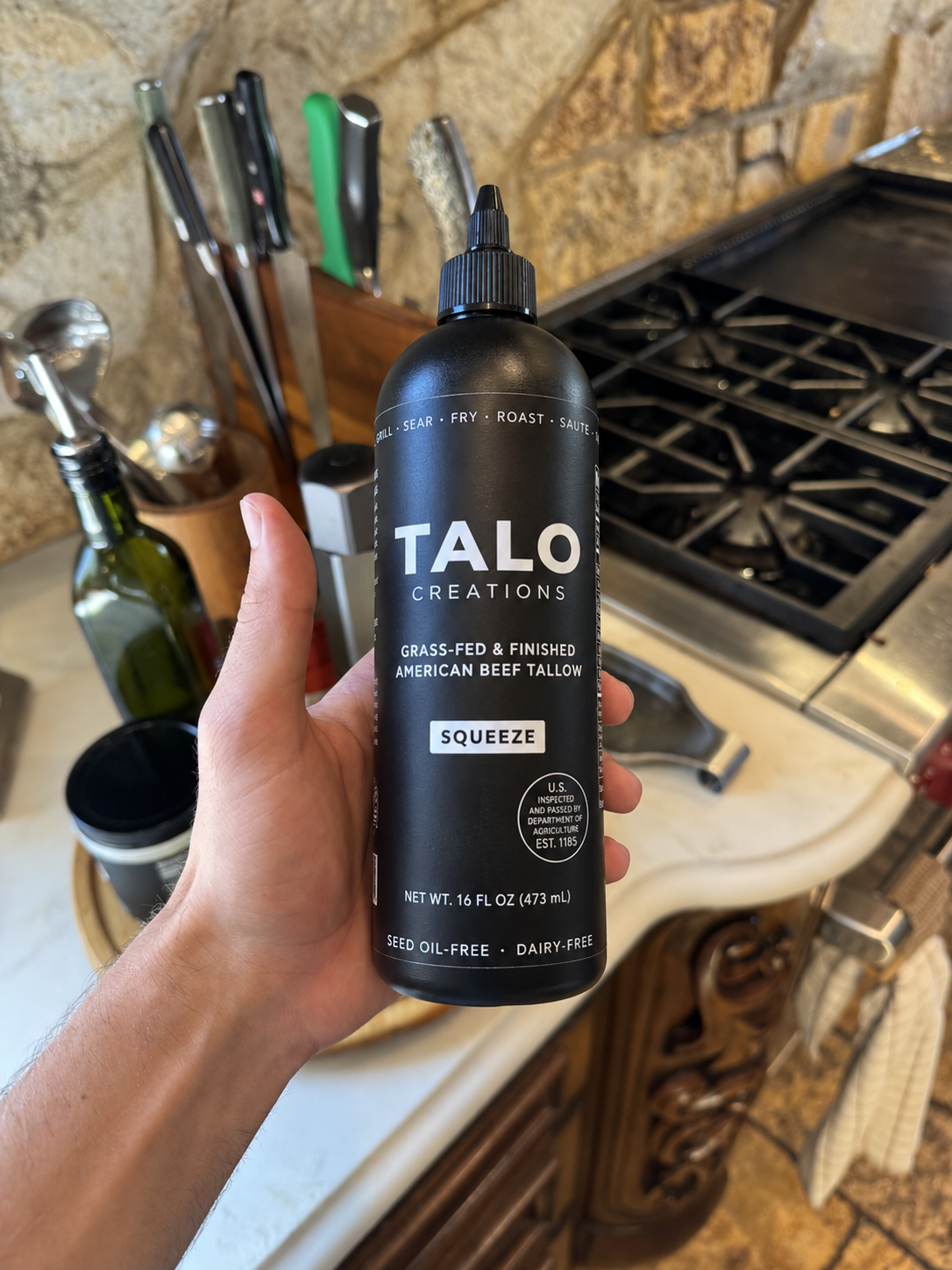 Holding the TALO Squeeze bottle in a home kitchen